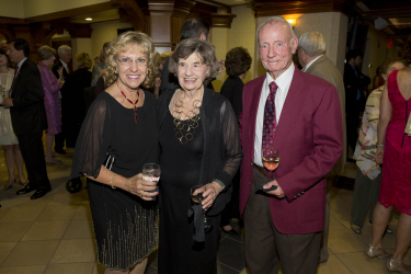 Three guests holding drinks and smiling