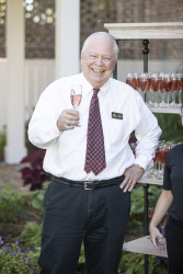 A staff member holding a wine glass and posing for a photo