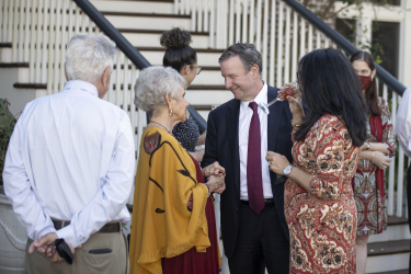 President McCullough and First Lady Jai Vartikar speaking with guests in front of a staircase