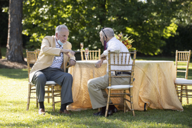 Two guests sitting down and chatting at a table outdoors