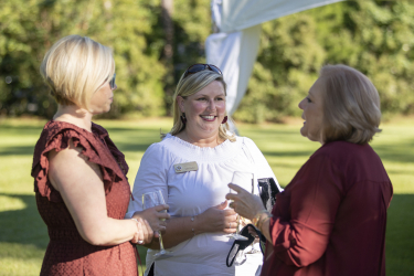 Julie Decker and two guests smiling and talking outdoors