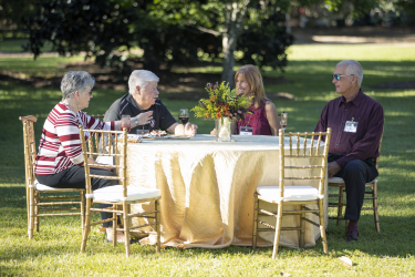 Four guests sitting down and chatting at a table outdoors