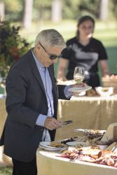 A guest with tongs picking food from a charcuterie table