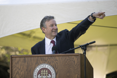 President McCullough at the podium smiling and pointing at the crowd