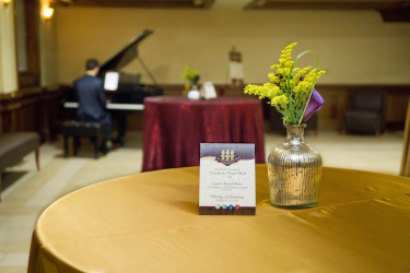 Tables with event cards and decorations in front of a piano
